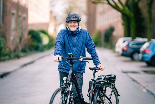 Das Bild zeigt Stefan Rütsch in einer blauen Regenjacke und mit seinem Fahrrad.