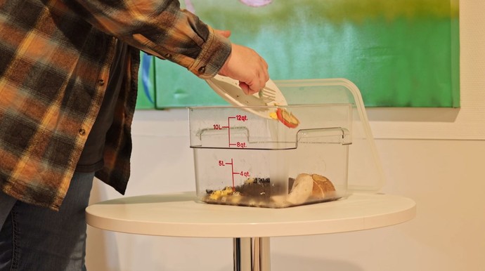Das Bild zeigt die Entsorgung der Speiseabfälle in die transparenten Behälter.