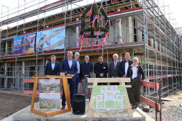Das Bild zeigt eine Gruppe Menschen vor der Baustelle des Klinikneubaus.